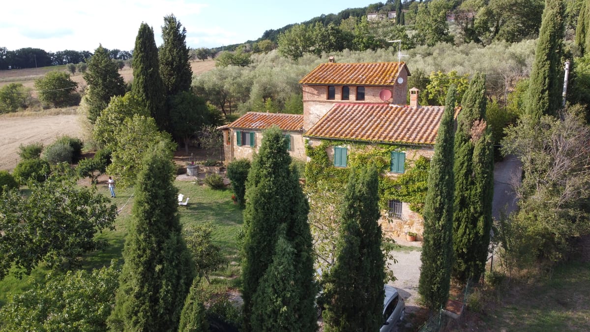 The farmhouse among cypresses and olive trees, seen by drone on a September morning