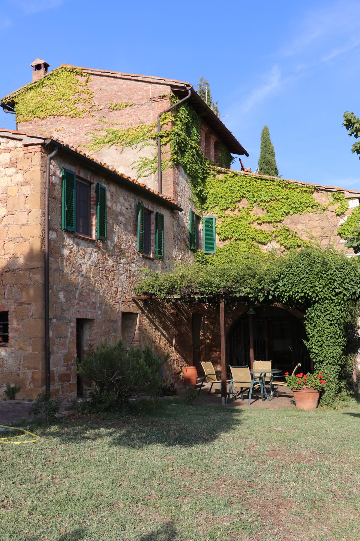 The archway thrown open onto the pergola: from the terracotta indoors to the brick terrace