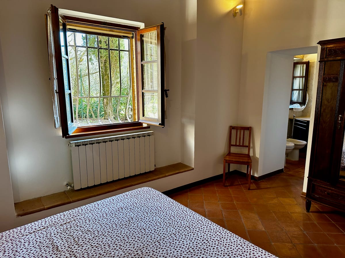 Morning light in the bedroom, with the bathroom glimpsed beyond