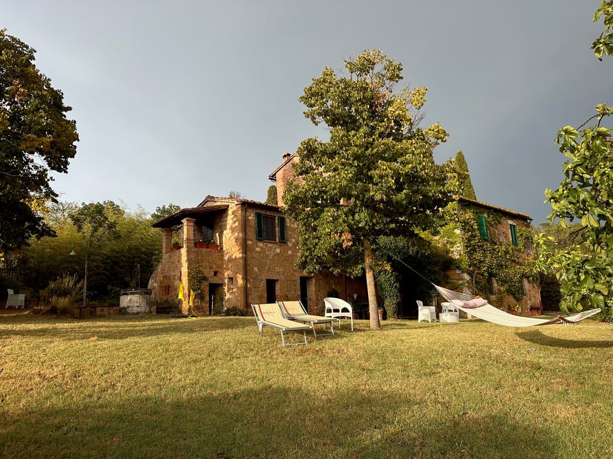 The farmhouse from the lawn, with loungers and a hammock in the shade