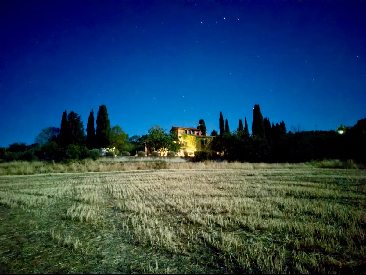 The farmhouse lit up at night under the starry Val d'Orcia sky