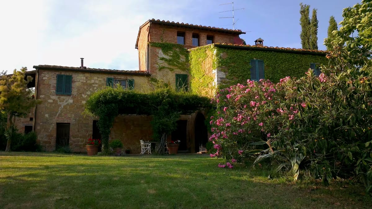 The stone façade of the farmhouse with ivy and a flowering oleander