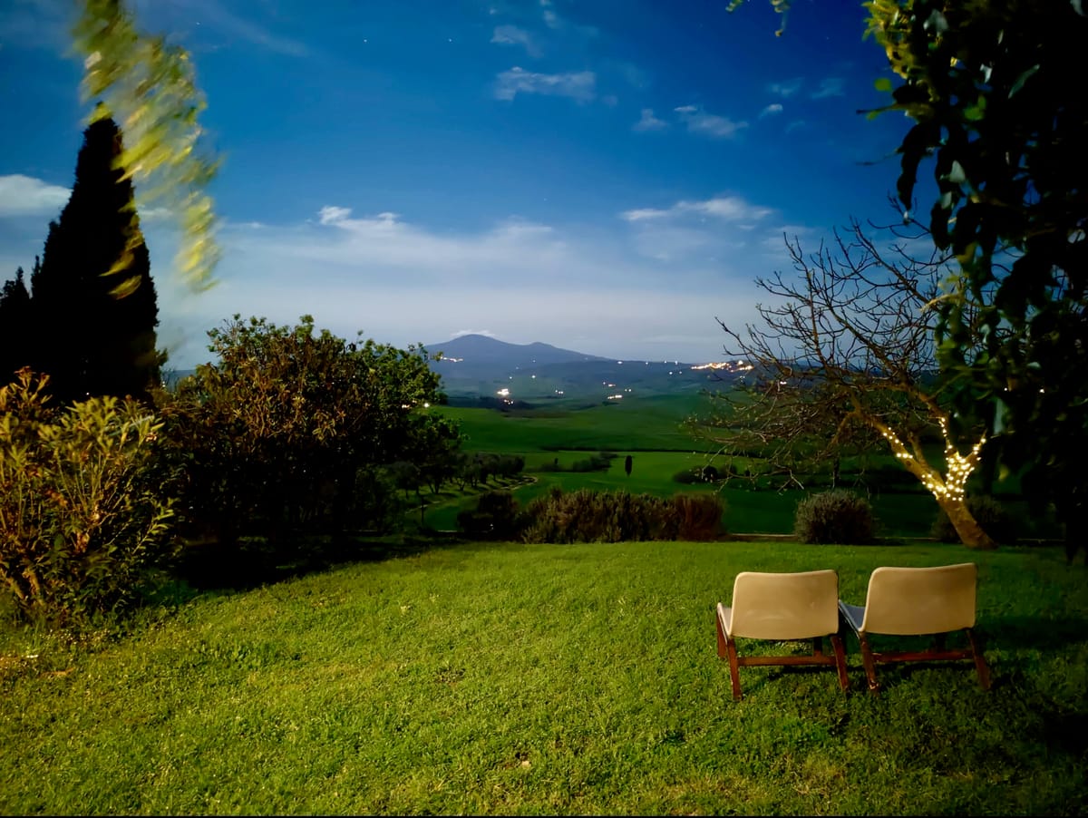 Two chairs on the lawn at dusk, facing the valley and Monte Amiata