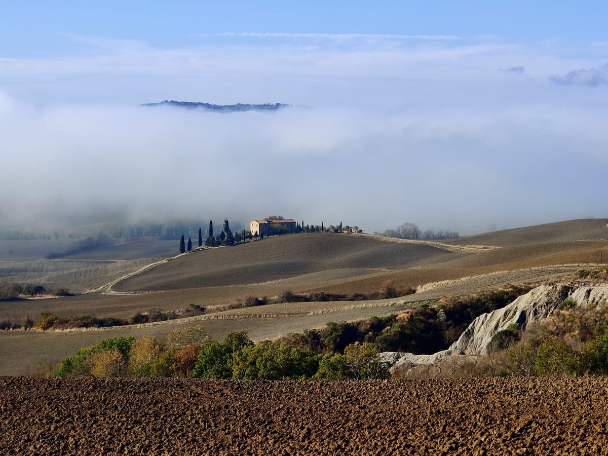 Morning mist filling the valley, a farmhouse above the clouds