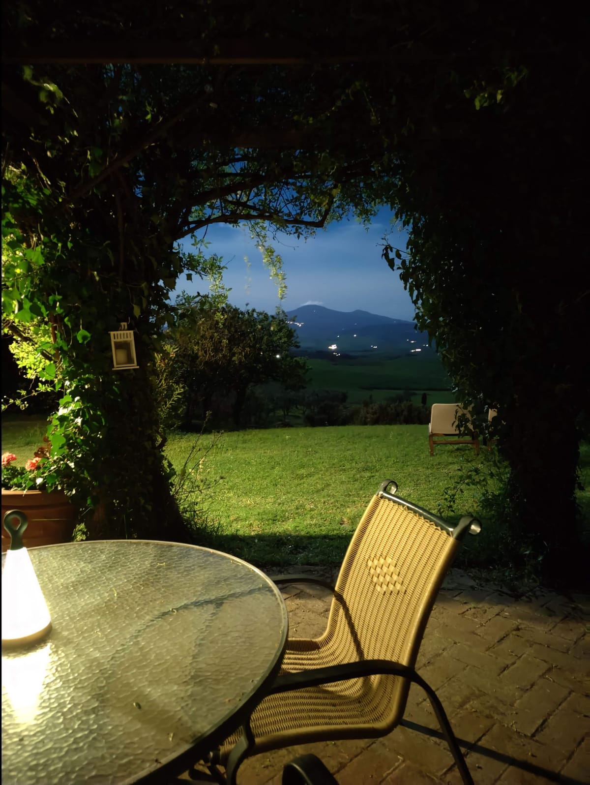 The pergola lit in the evening, the table laid and the dark valley beyond